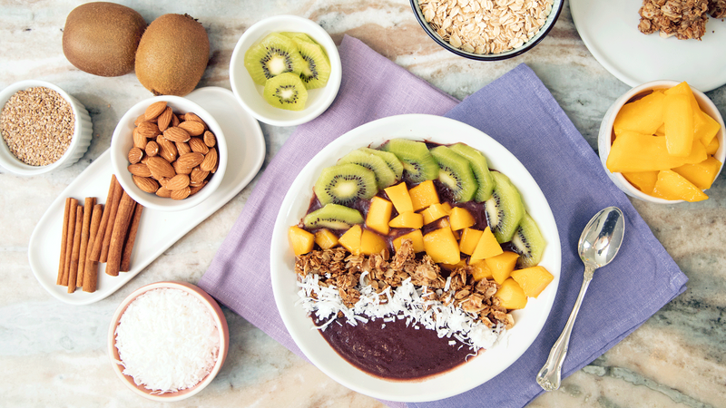 Fruit bowl with various toppings on a wooden table